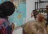 Dzieci w klasie uczą się geografii przy dużej mapie świata