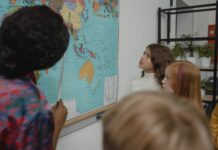 Dzieci w klasie uczą się geografii przy dużej mapie świata