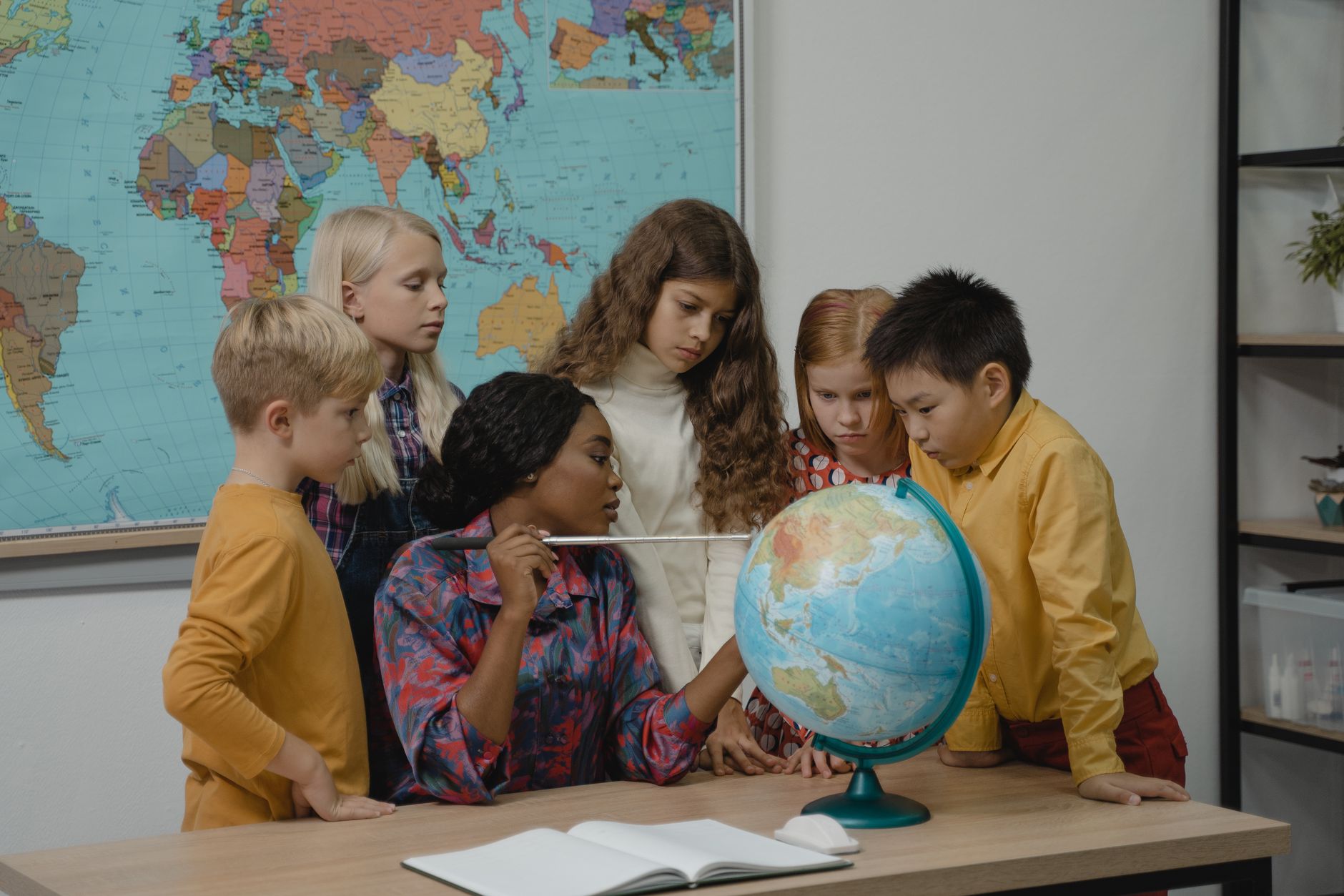 Nauczyciel pokazuje globus grupie dzieci na lekcji geografii