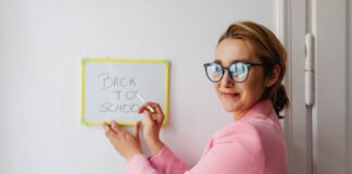 Nauczycielka w różowej marynarce pisze na tablicy Back to School