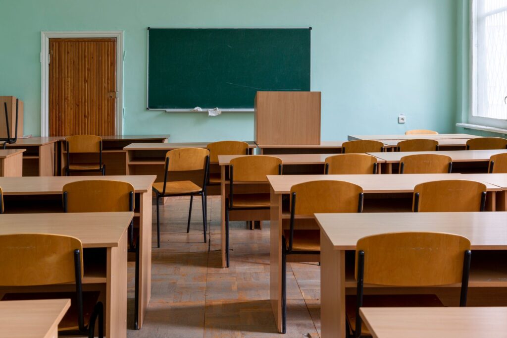 Pusta sala lekcyjna z drewnianymi ławkami i zieloną tablicą